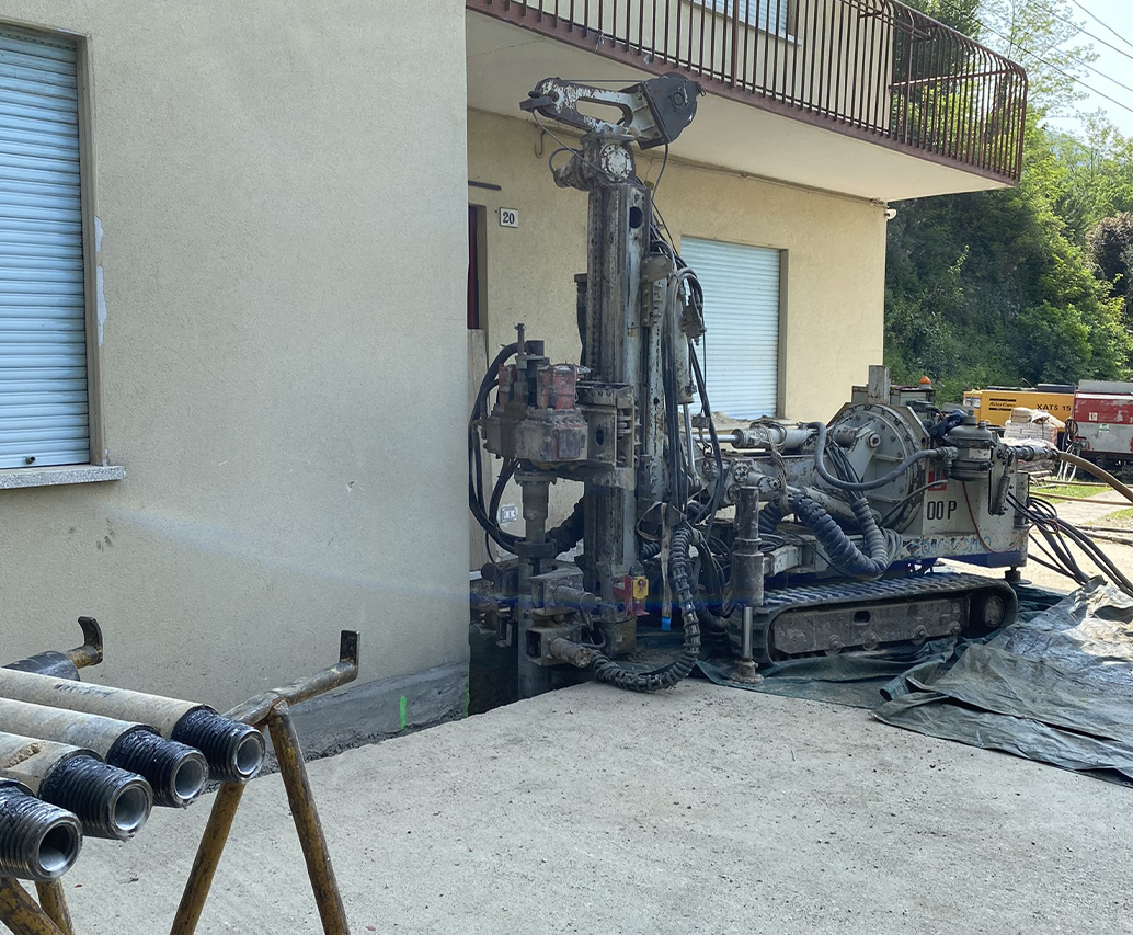 Escavatore con trivella al fianco di edificio