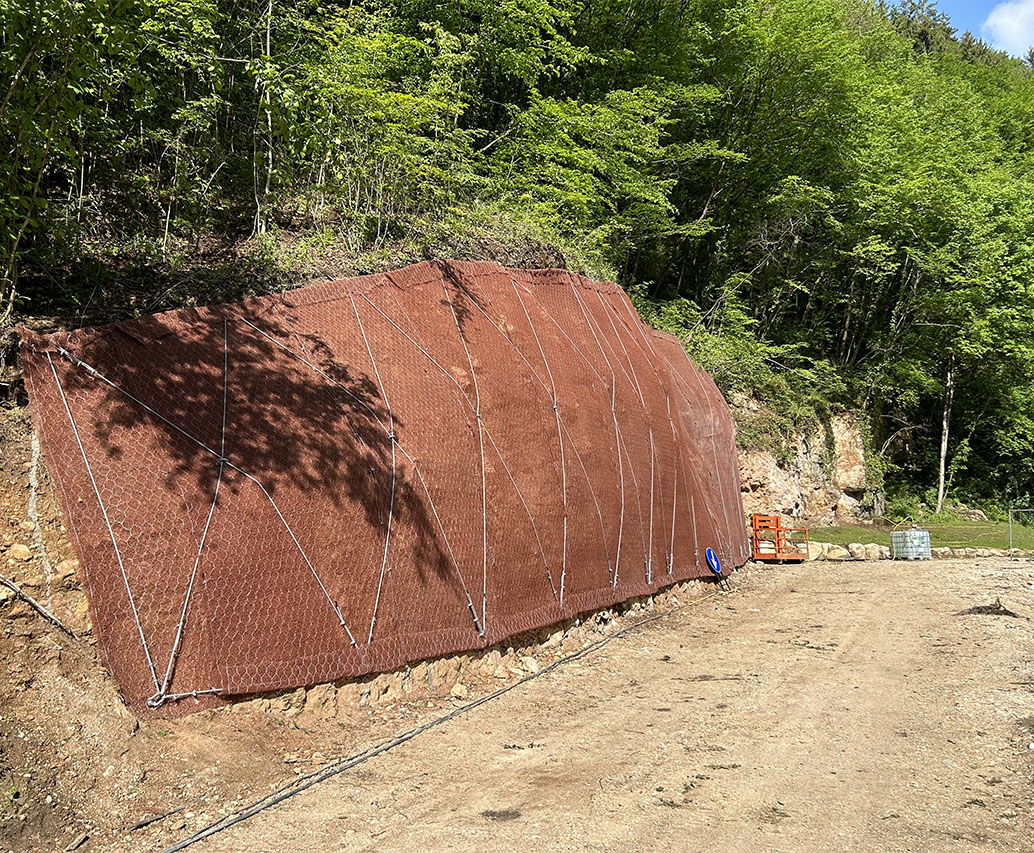 Barriera paramassi in rete metallica marrone installata in bosco
