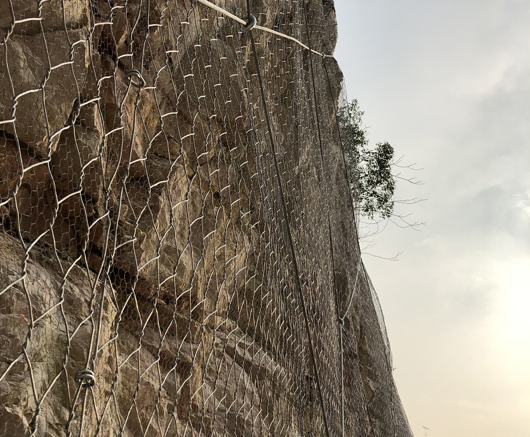 Primo piano di rete metallica esagonale su parete rocciosa