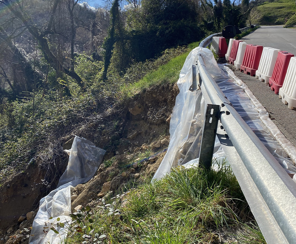 Pendio con rete geogrid e escavatore in cantiere