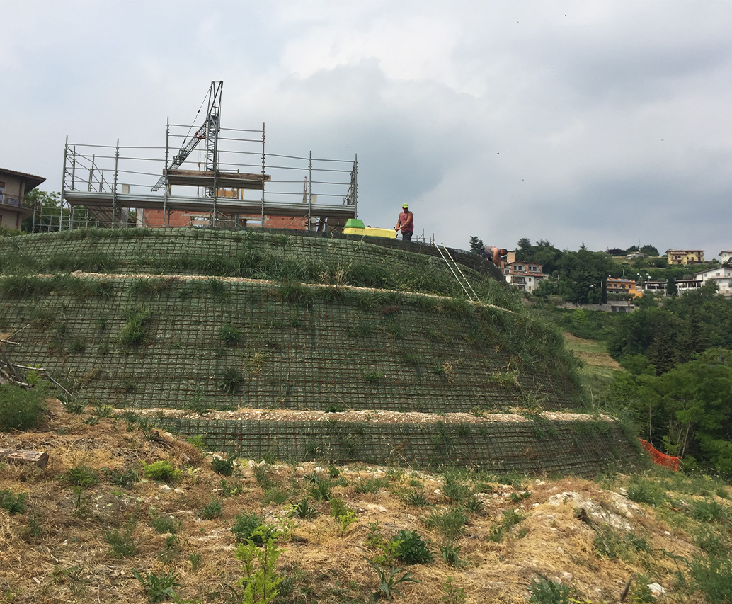 Mini escavatore posa geogriglia su pendio